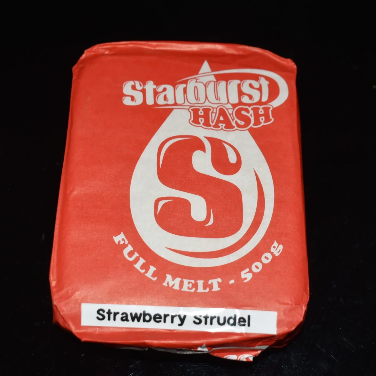 Pale pressed Strawberry Strudel Hash slab on parchment with a small rolled piece 6